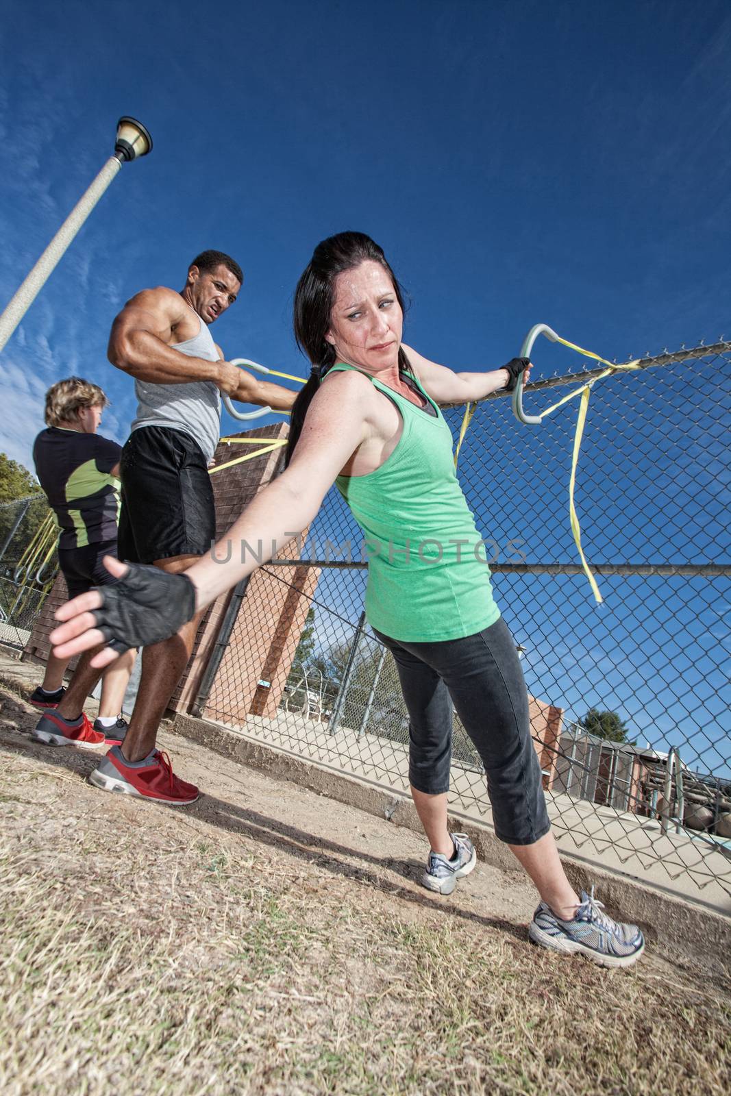 Three adults using resistance bands in outdoor fitness class