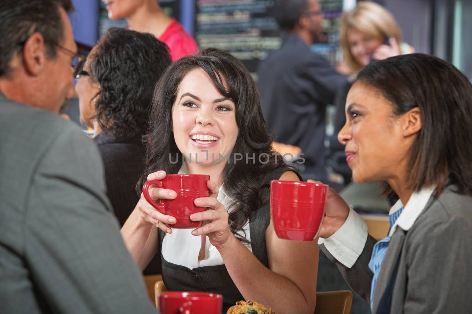 Smiling woman with coffee and friends in bistro