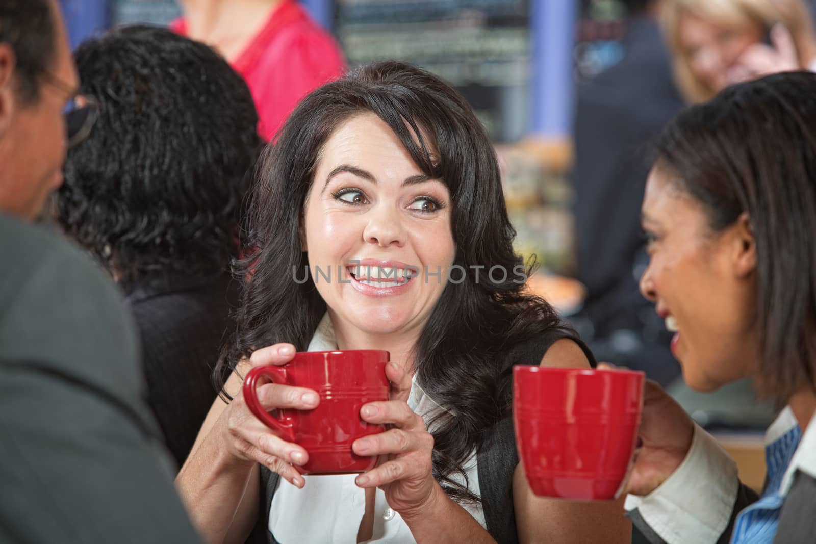 Happy adult female with coffee and friends in cafe