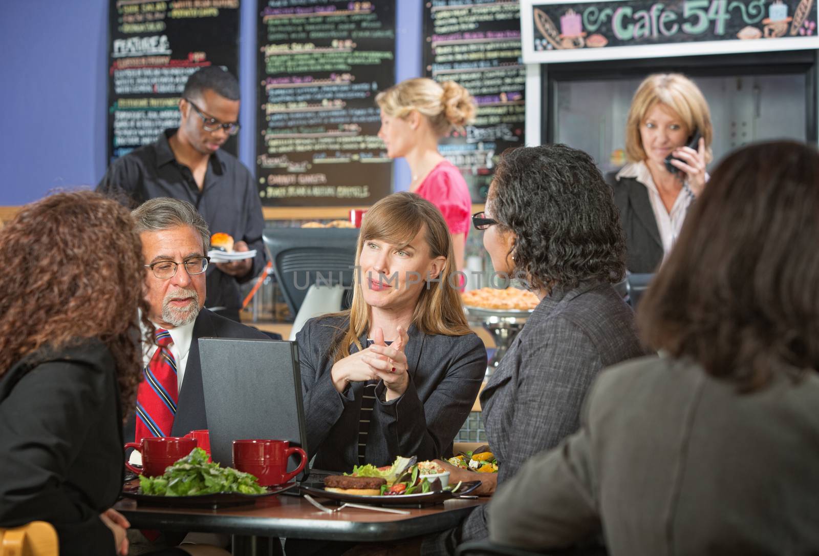 Smiling female executive eating lunch with coworkers