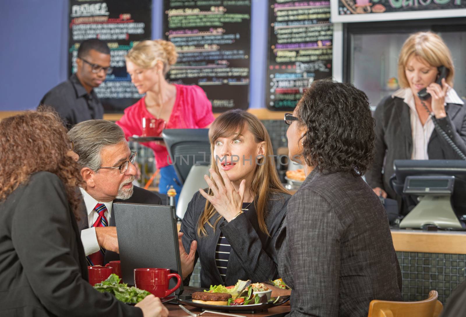 Surprised beautiful white collar worker with diverse group in cafe