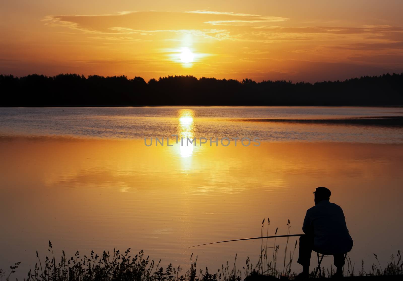 Fisherman silhouette. Sunset over the lale