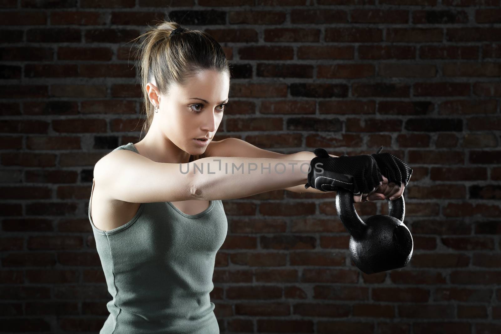 Portrait of Young fit woman lifting kettle bell 