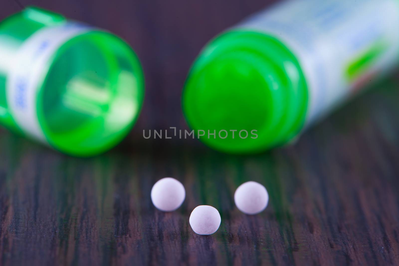 White granules of homeopathic medicine, over wooden table
