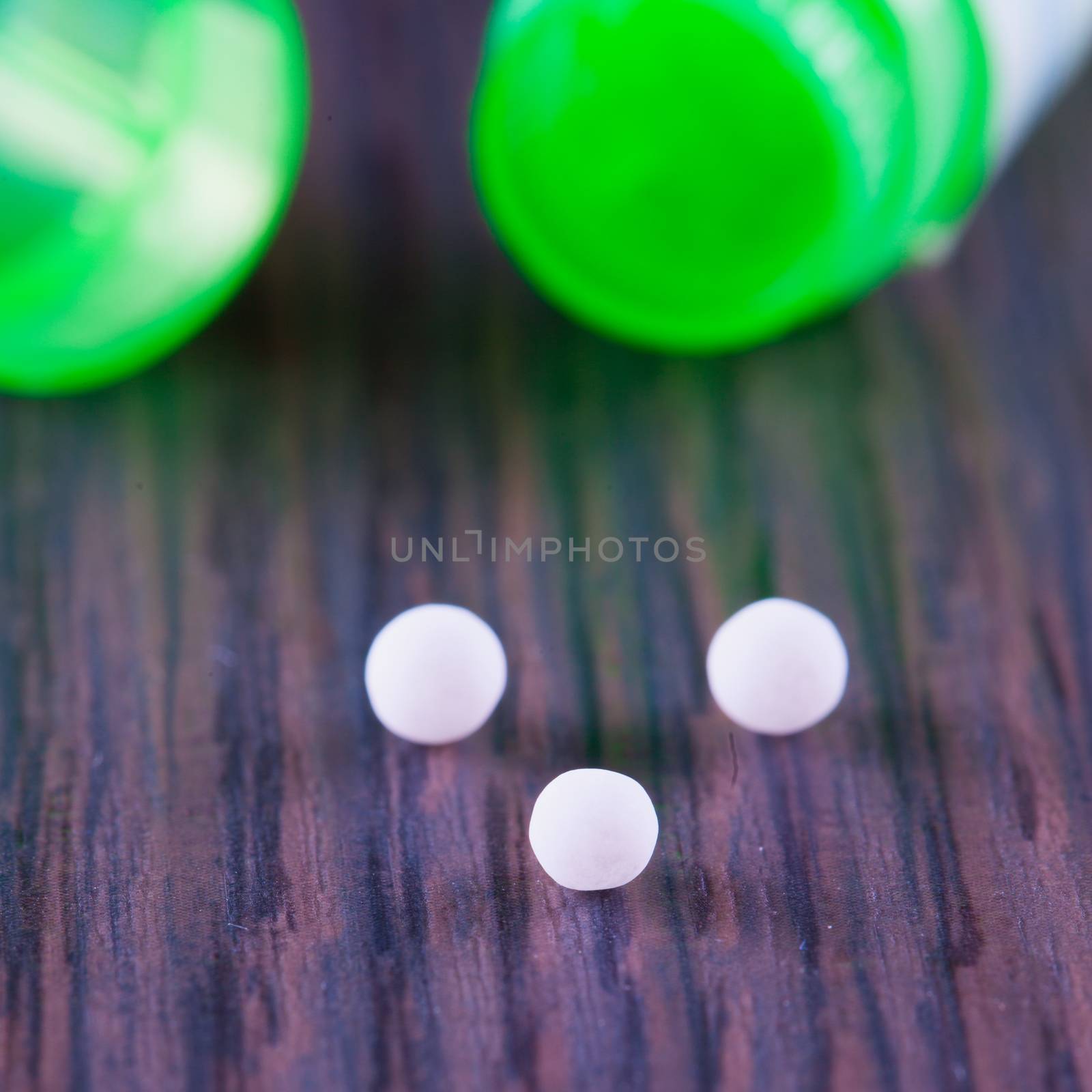 White granules of homeopathic medicine, over wooden table