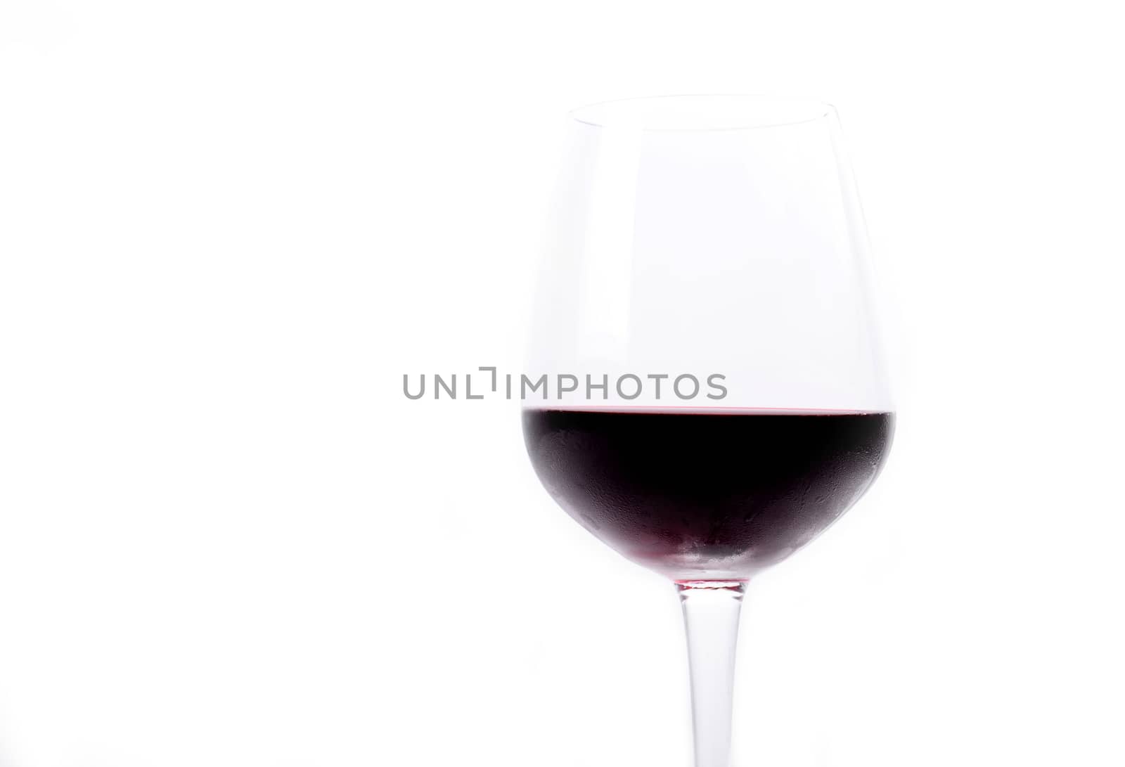 Red wine pouring in a wineglass on white background