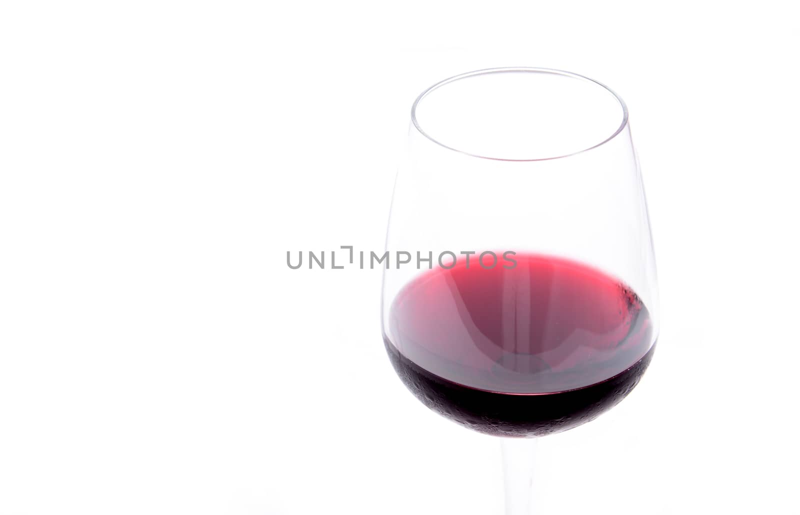Red wine pouring in a wineglass on white background