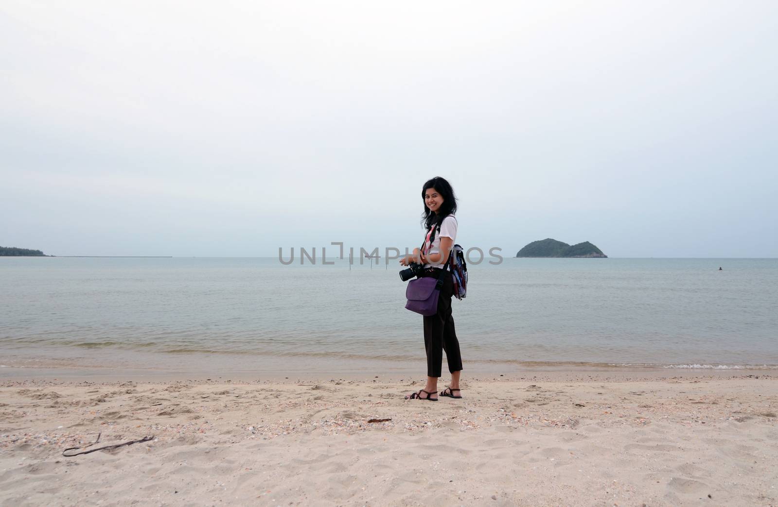 Happy young woman with dslr camera on the beach