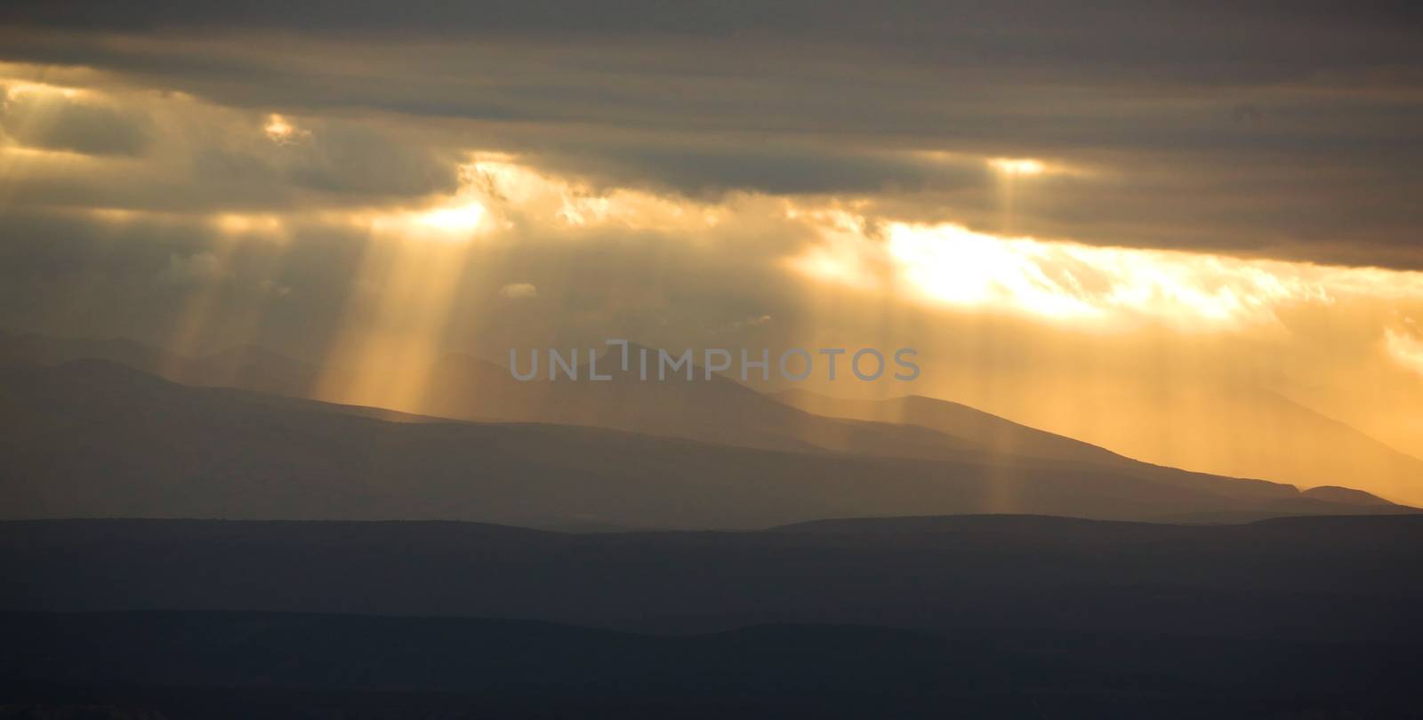 Rays of evening sun shining down through the clouds on to mountains