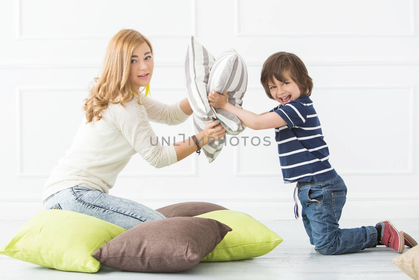 Cute, adorable boy with mother fighting with pillows