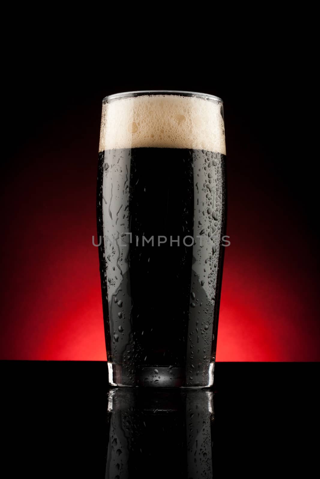 glass of black beer with reflection and water drops