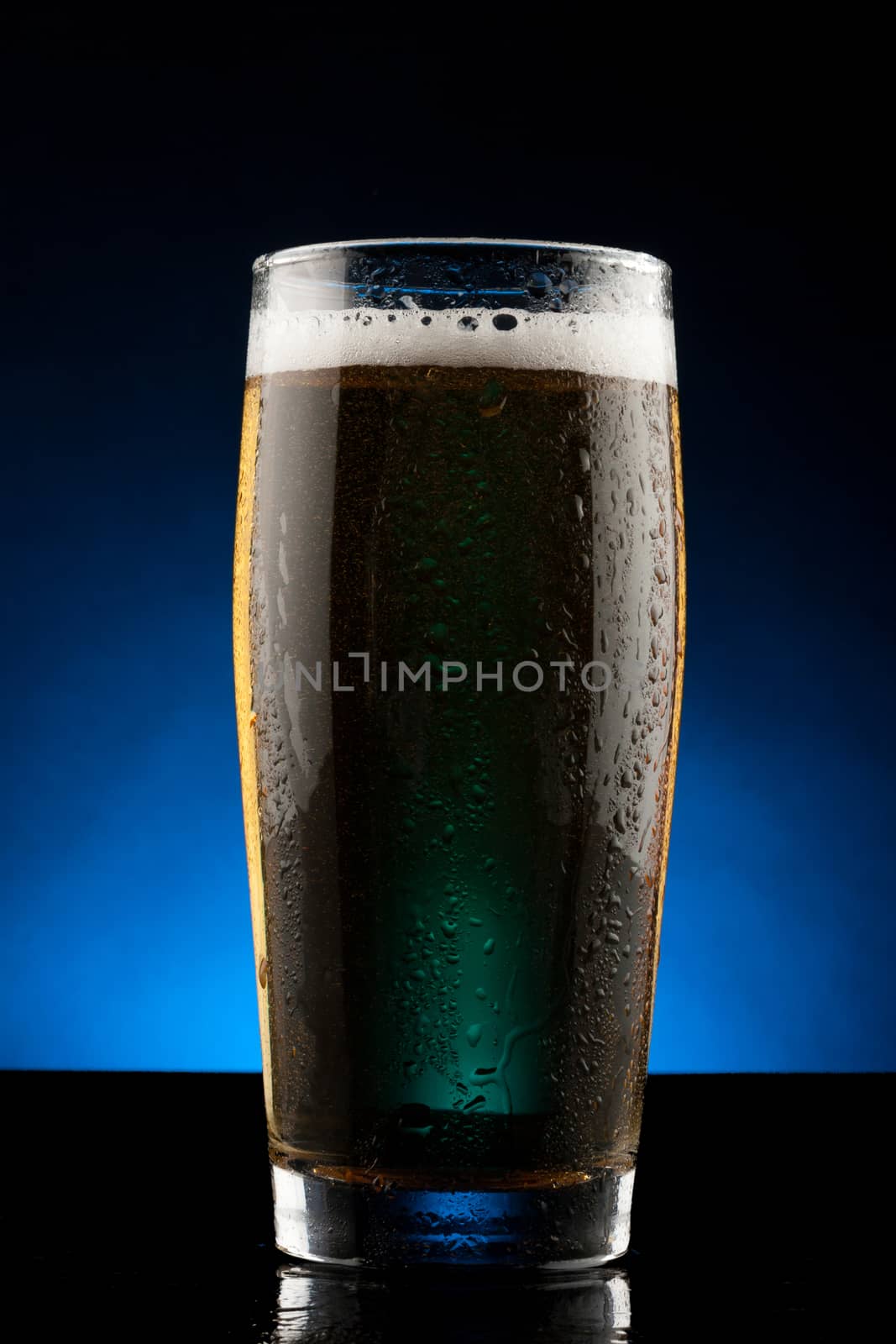 back lit glass of beer with water drops