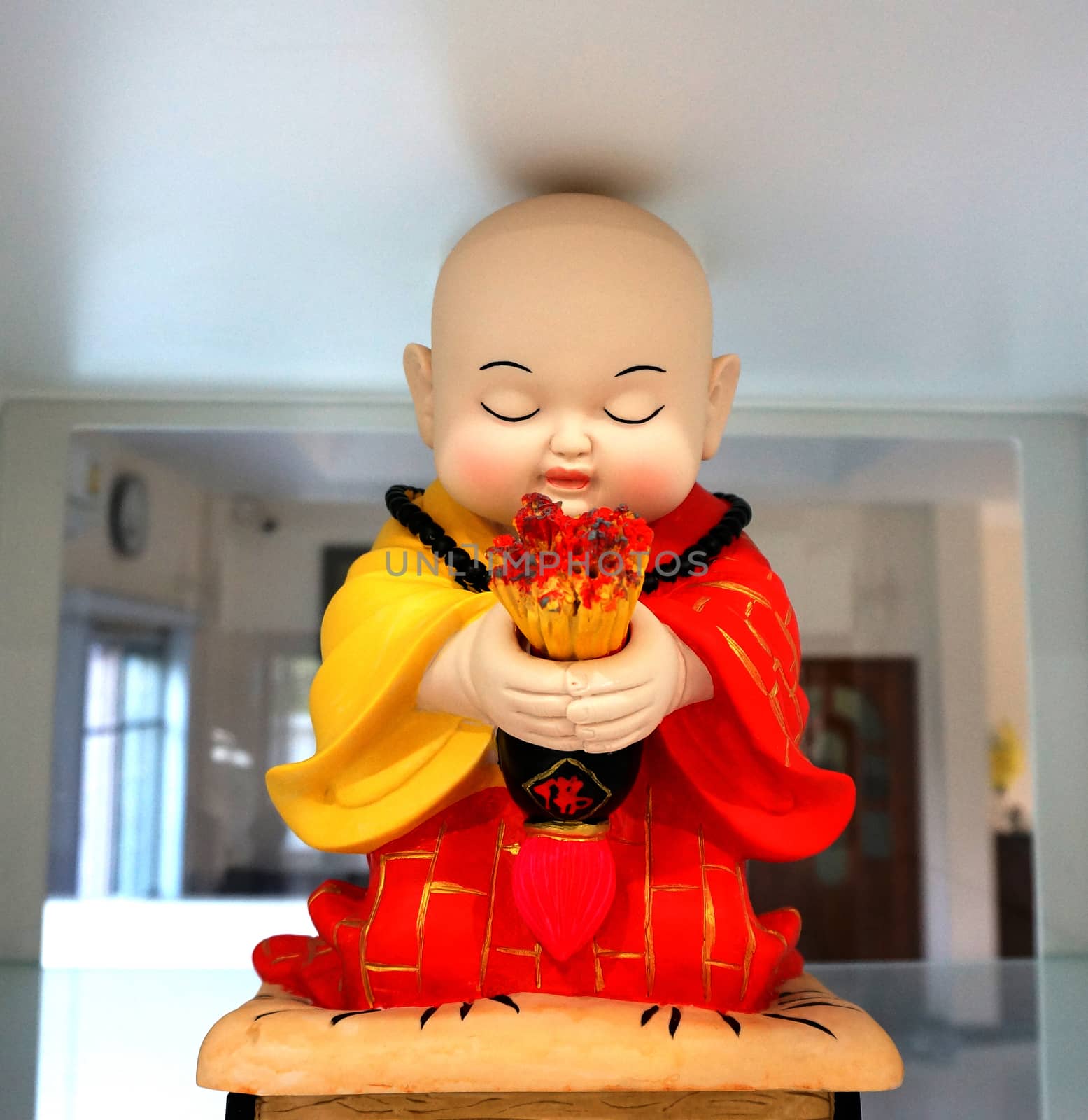 The little monks, wear the yellow and red robe, Chinese style. Hands holding incense is sitting with eyes closed, prayer intentions.                             