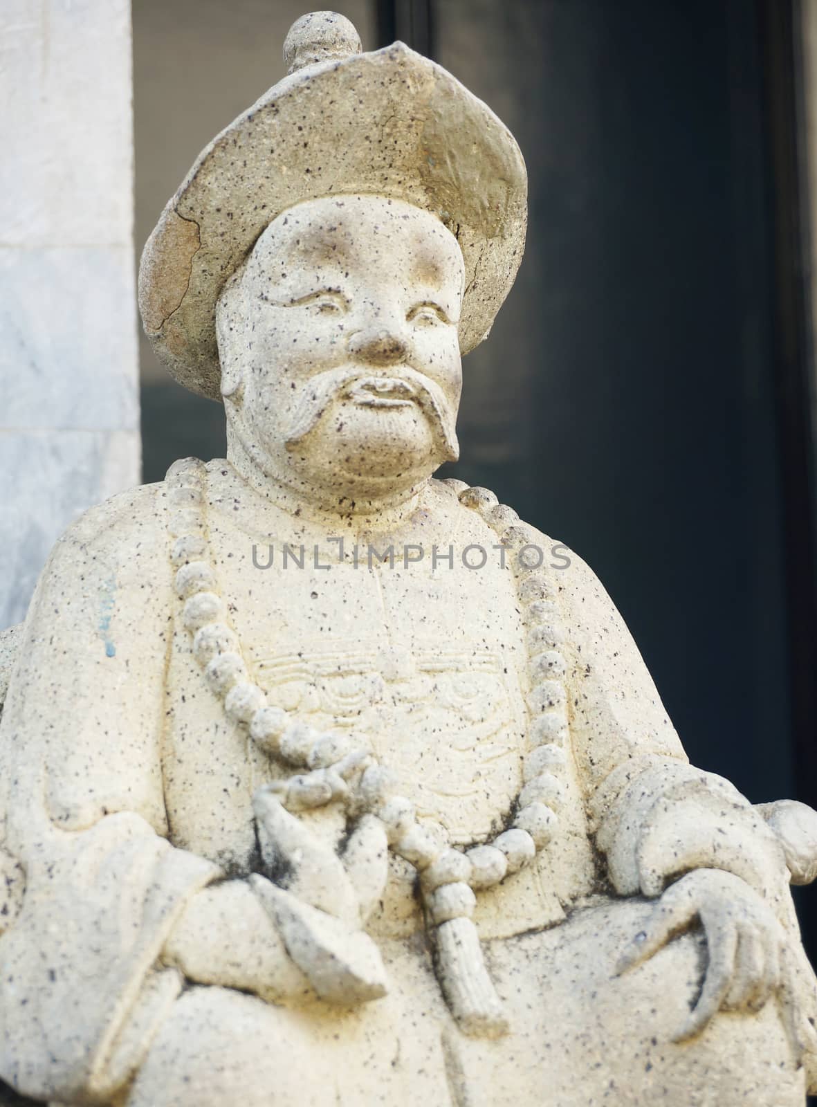 Old, ancient Chinese stone figures. Figure shows the costumes in the past. Is the beam length robe, wearing a narrow-brimmed hat, wearing the rosary as jewelry, a progressive face                             