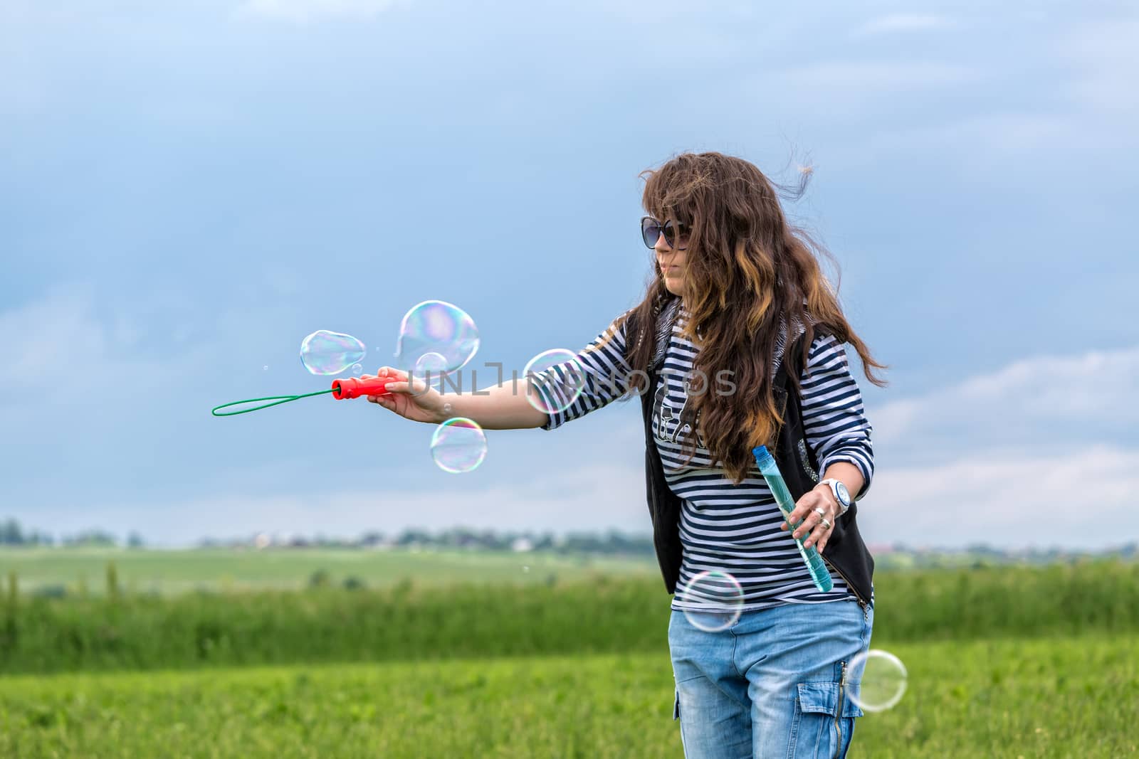 Beautiful Young Woman make Blowing Bubbles, on green grass