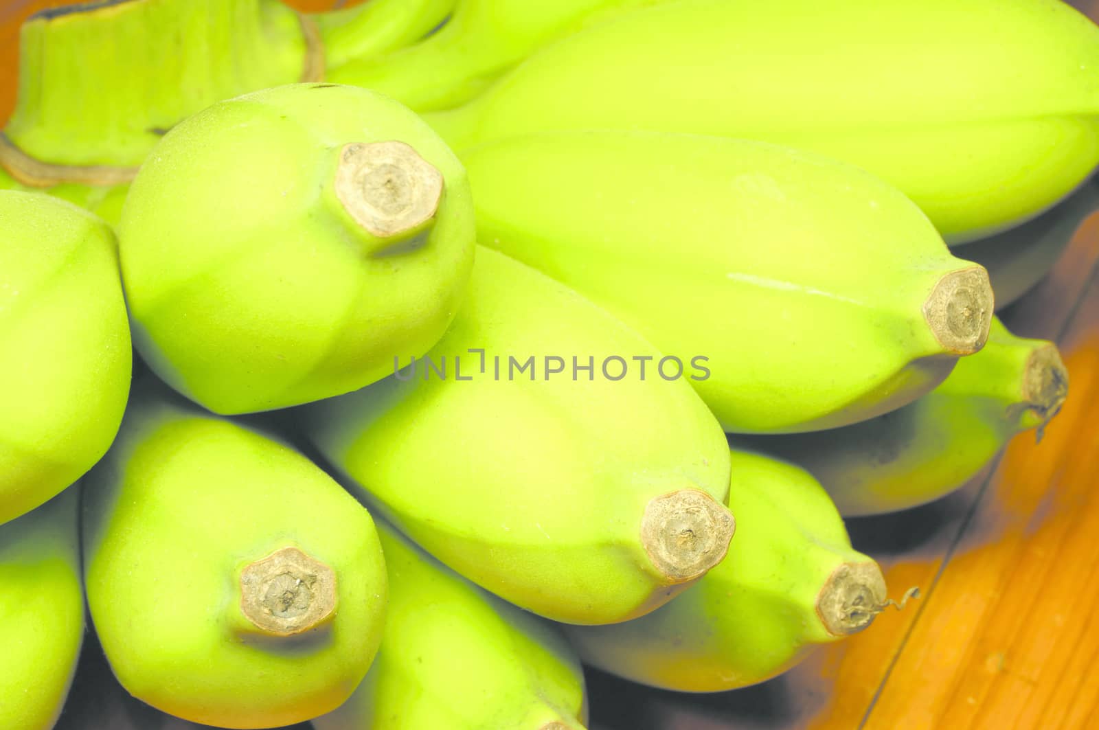 Green banana on wooden table by ninun