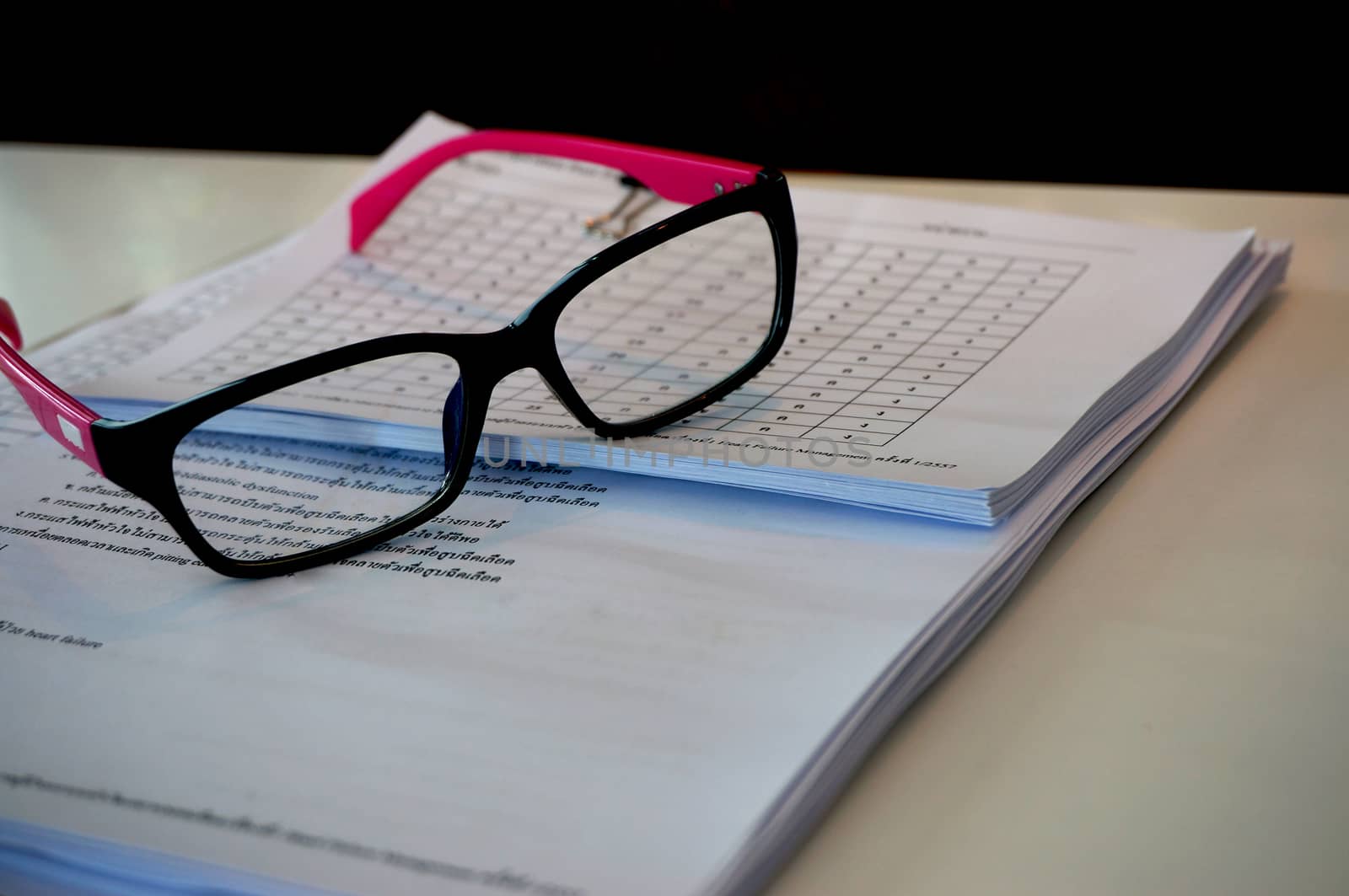 The glasses placed on the documents stored orderly. On the desk at office.                              