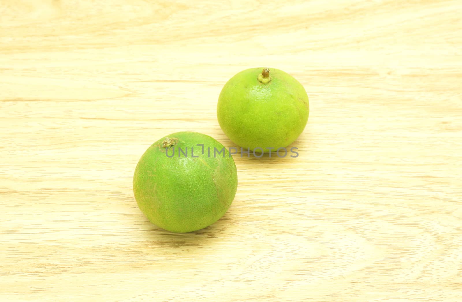 Two lime green is not cut off, placed on a wooden table                               