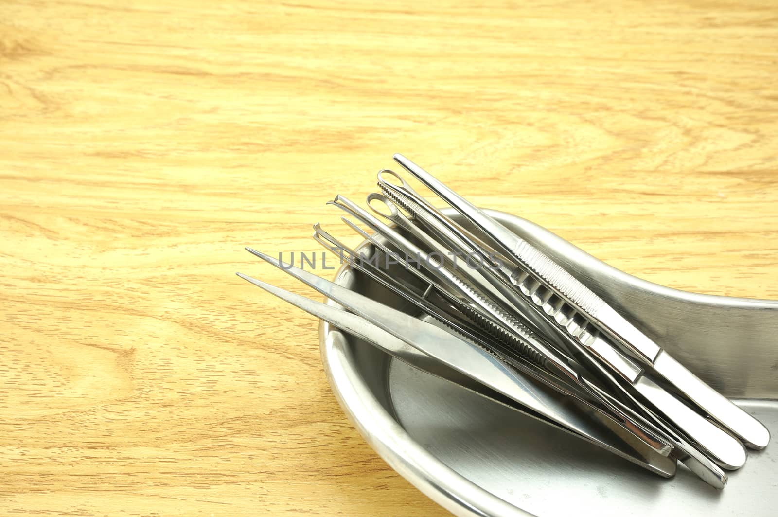 Many types of forceps made of stainless steel and placed in a bowl-shaped kidney.                              