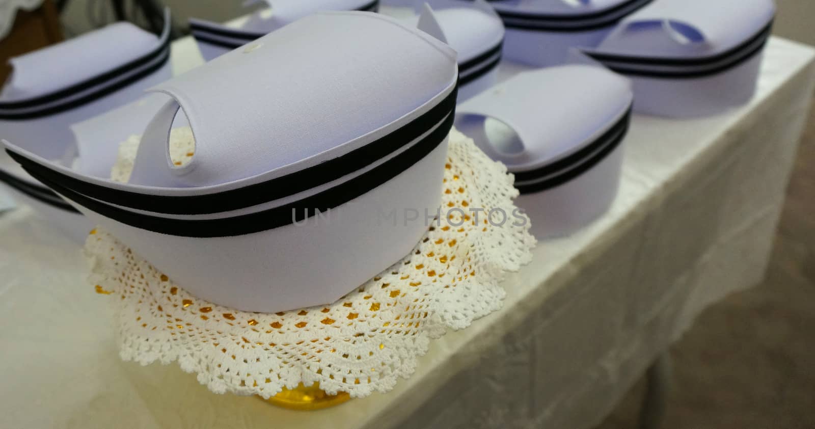 White nurses hat and a black stripe, Placed on a table that overed with a white tablecloth.                              
