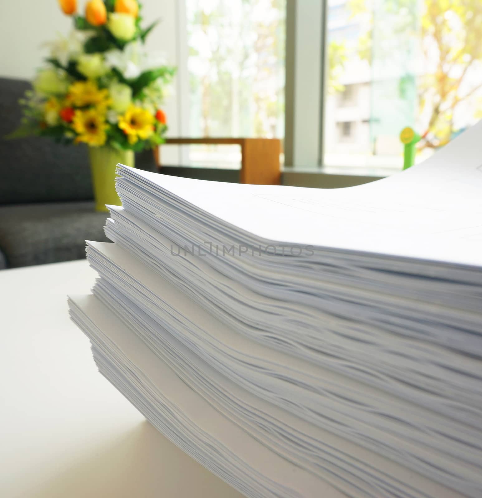 Many large sheets of white papers stacked as a set, placed on desk.                              