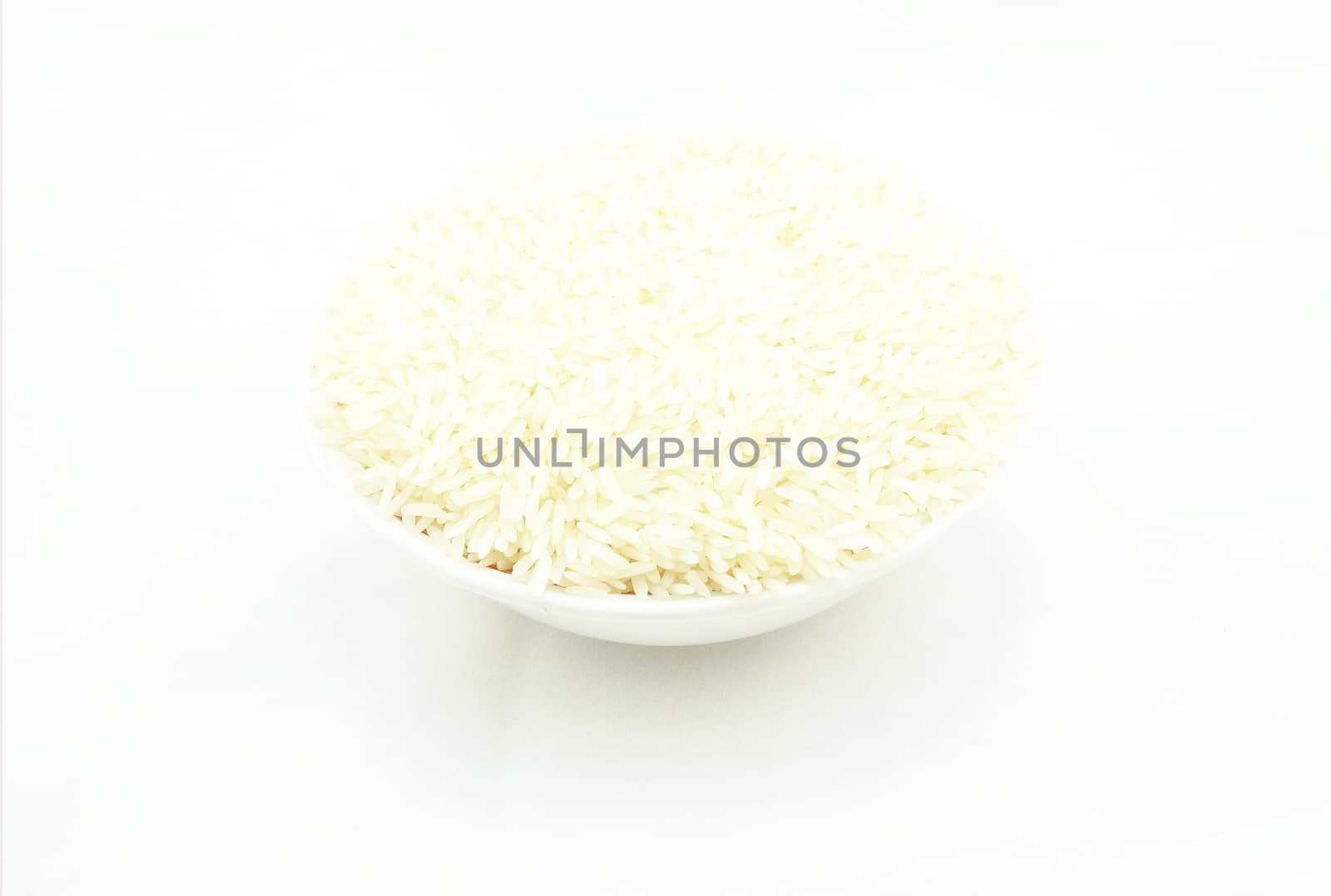 Uncooked rice, put in bowl. Placed on a white background.                               