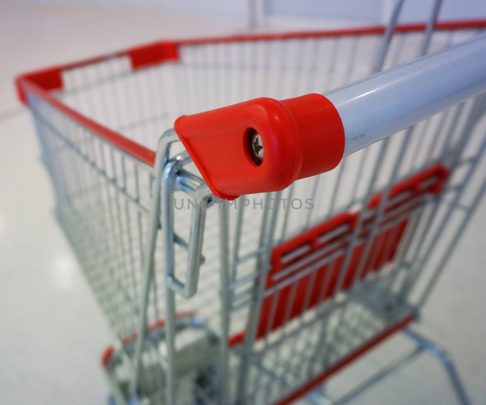 Shopping cart in the mall, area of ??the handrails made ??of red plastic and wheels for easy accessible.                           