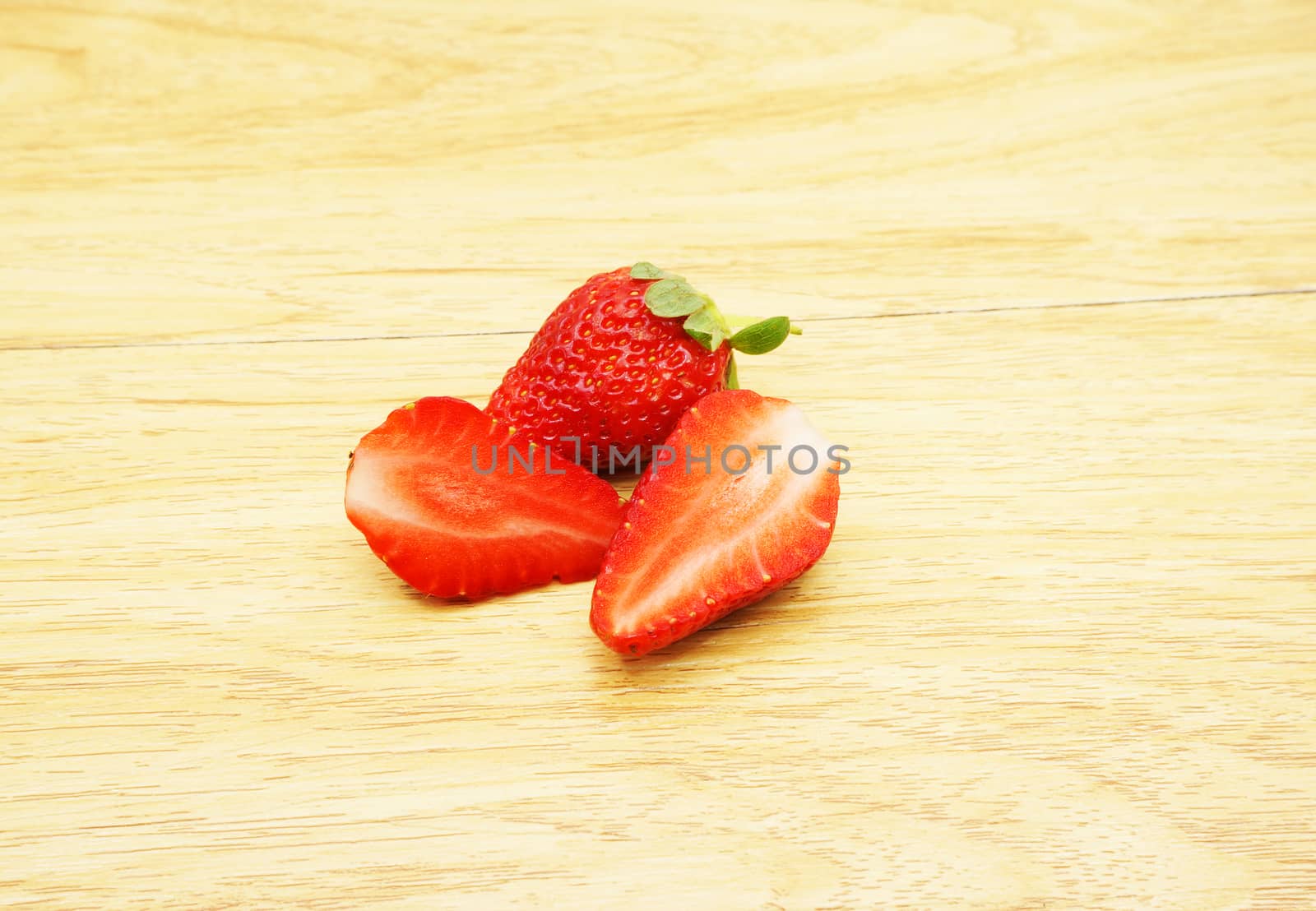 Two fresh strawberries, were cut in half and the other one was not cut, put together                              