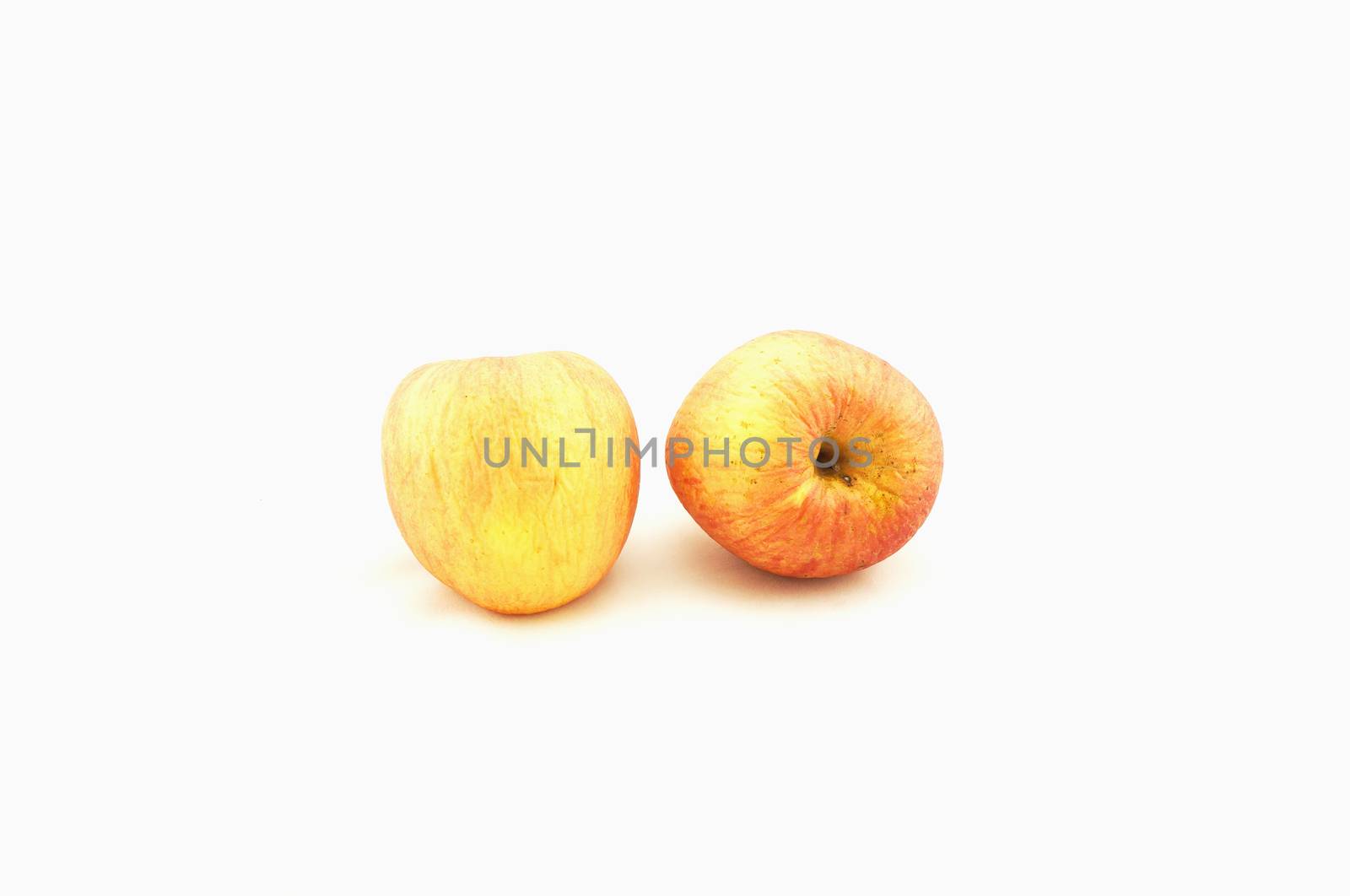 Two apples,the skin is starting to wrinkle, placed together on a white background.                             