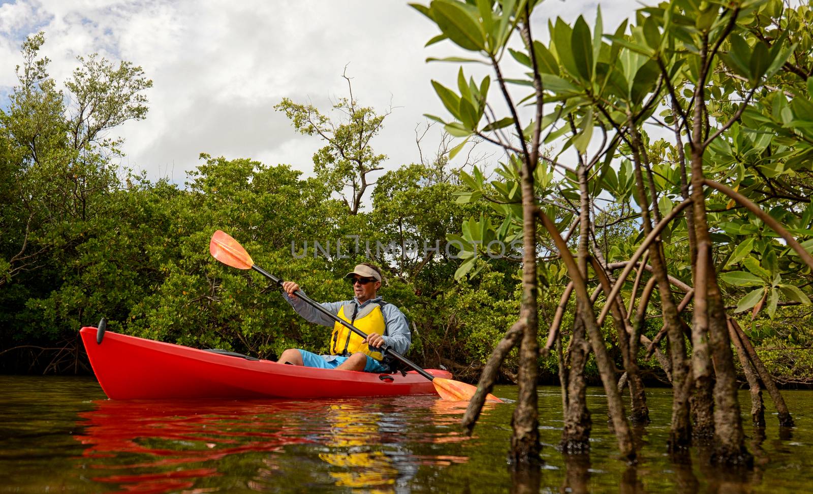 man in a red kayak through the mangroves in a tropical destination