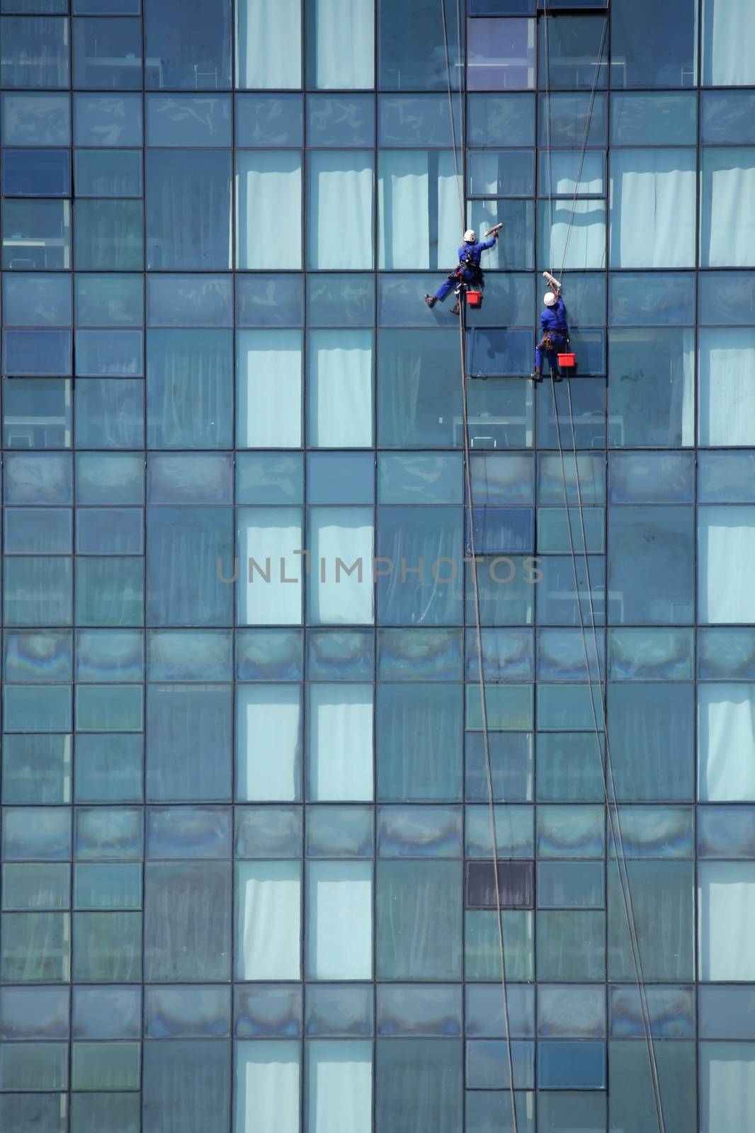 Two window cleaner men high up on the outside of a building