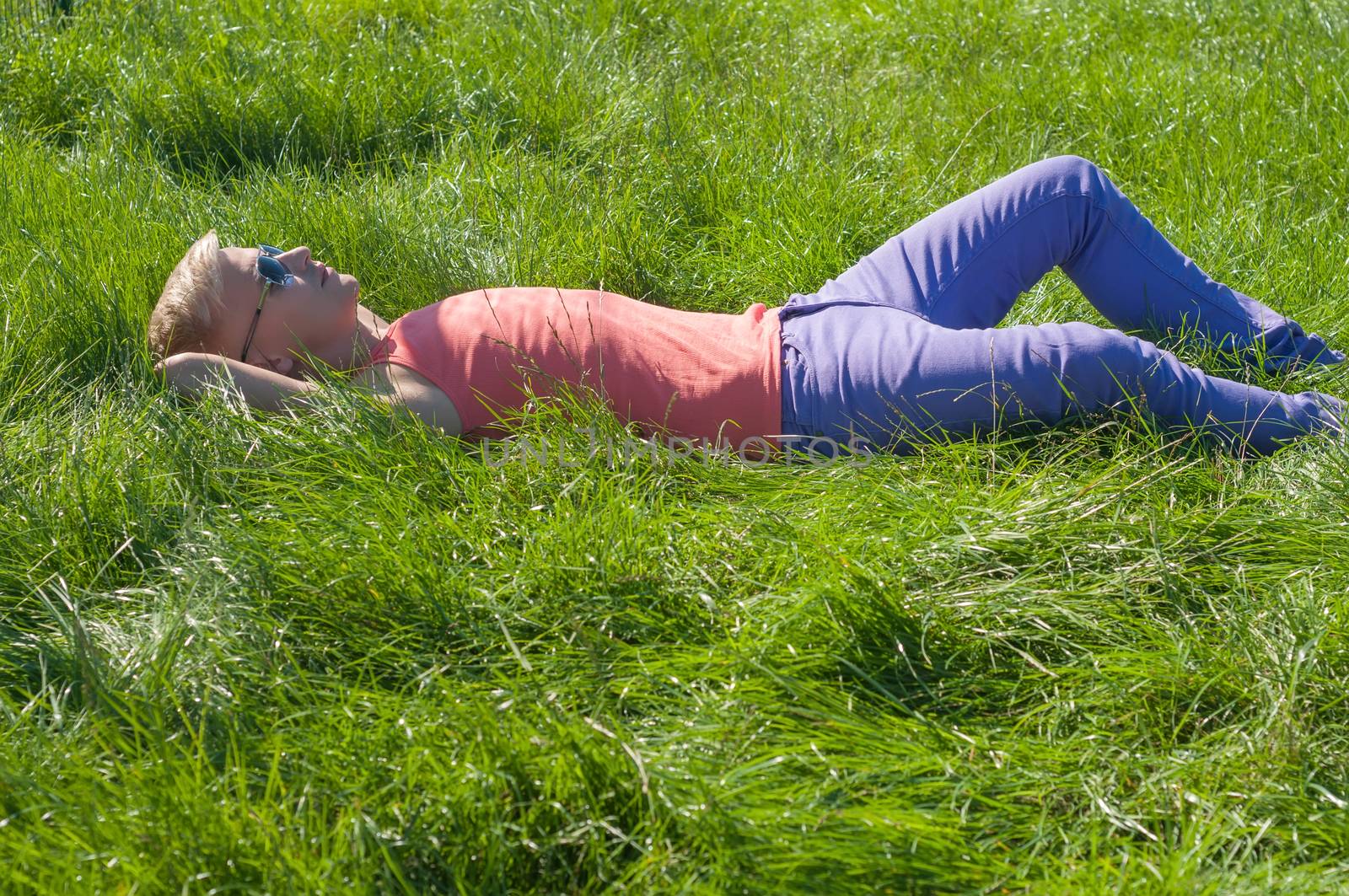 Young man in sleeveless sports shirt lying on the grass