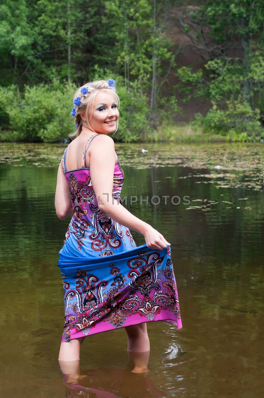 Beautiful woman in long dress standing in pond