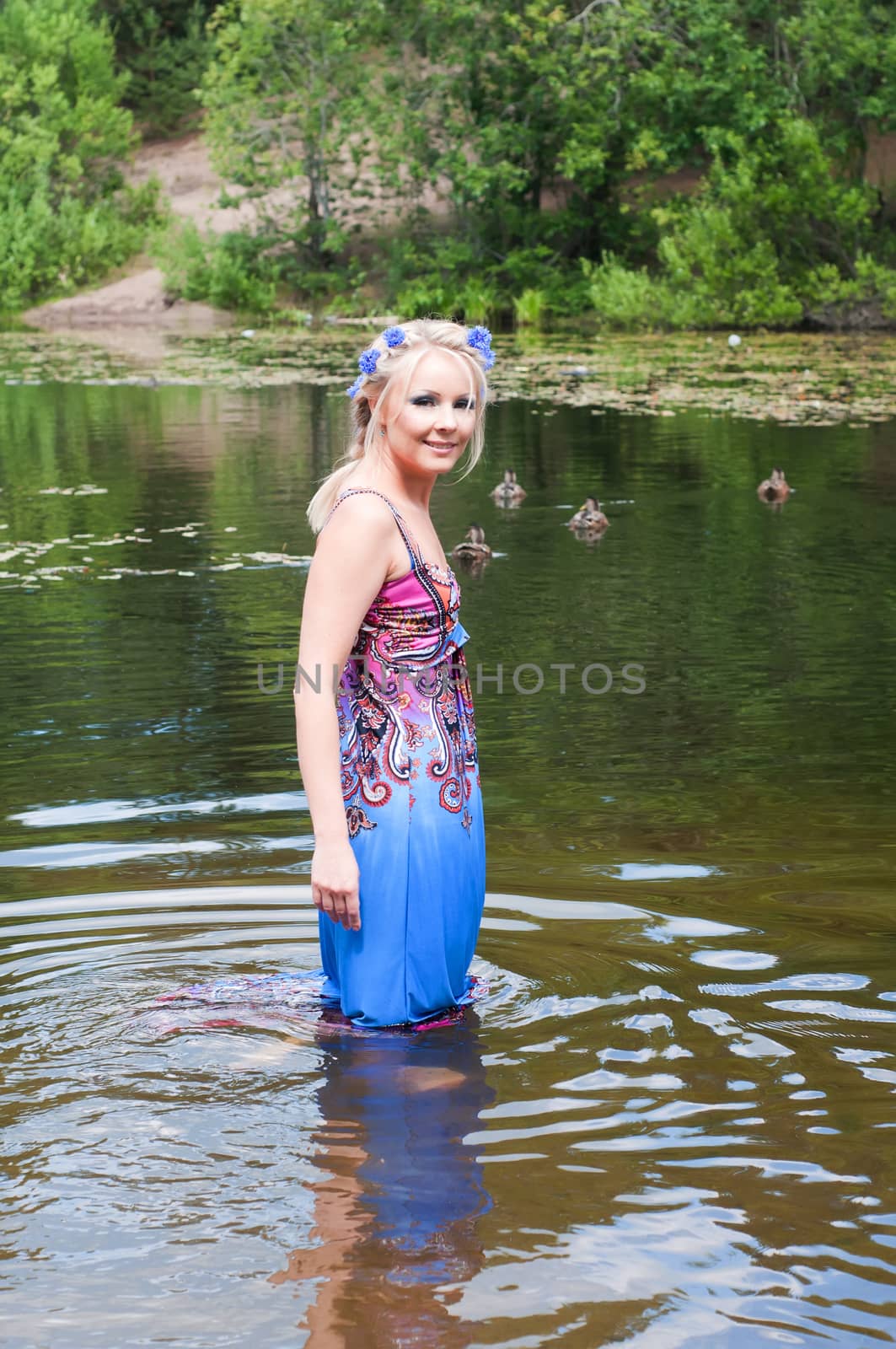Beautiful woman in dress standing in pond by anytka