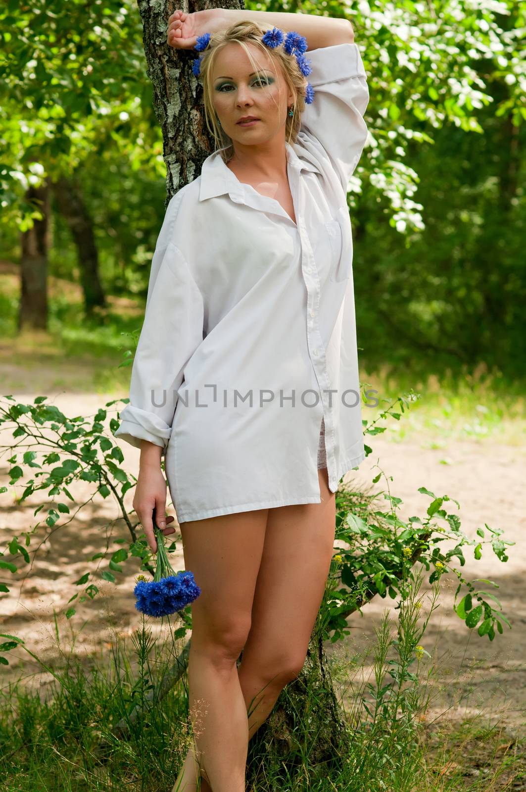 Beautiful young woman in white shirt standing near the tree