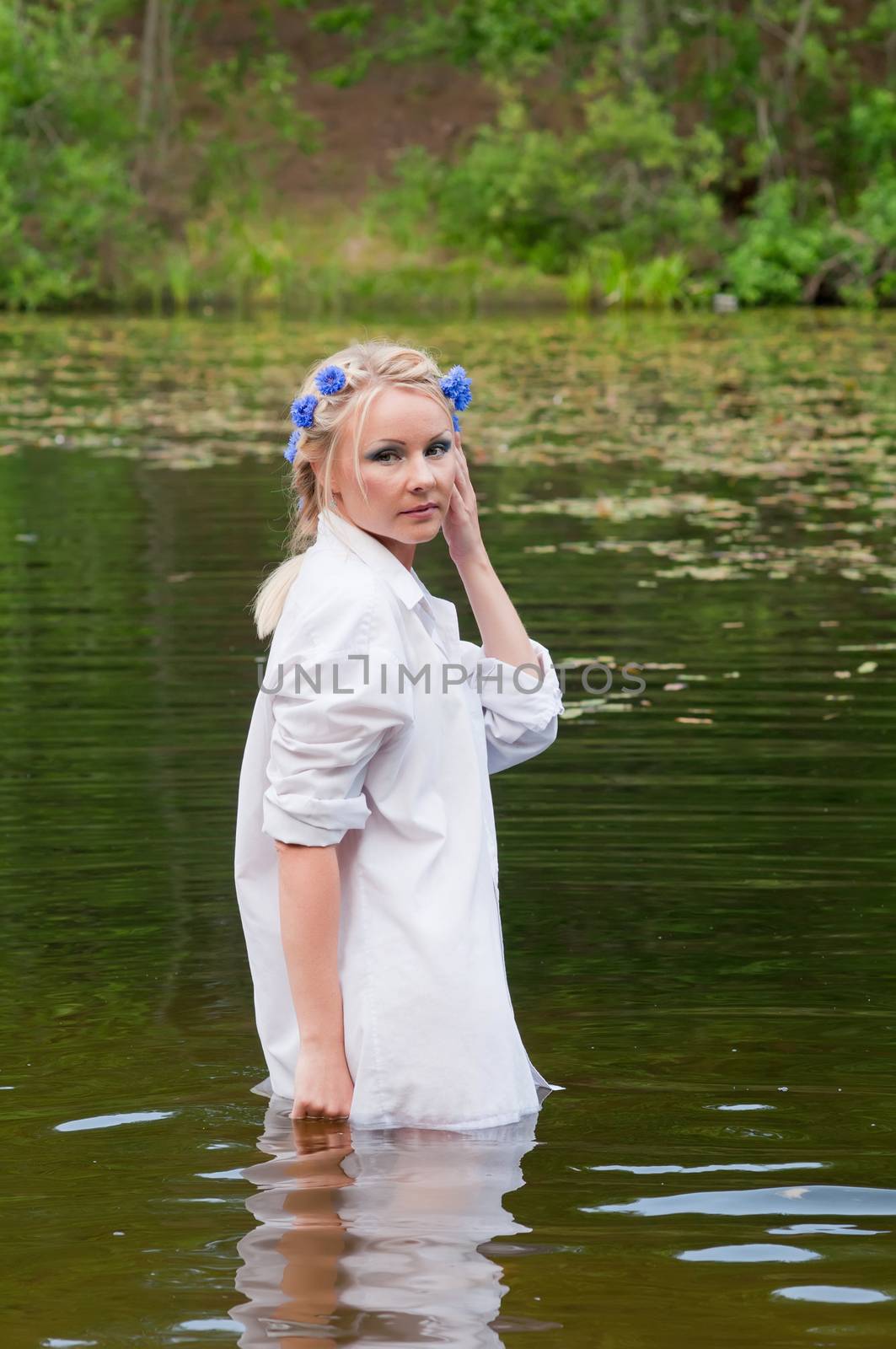 Beautiful woman in white standing in pond by anytka