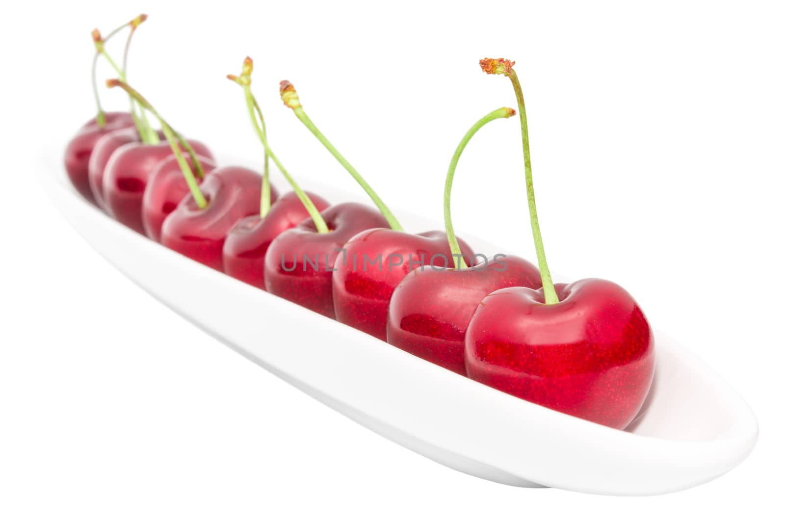 Appetizing ripe cherry berry row on long olive dish isolated on white