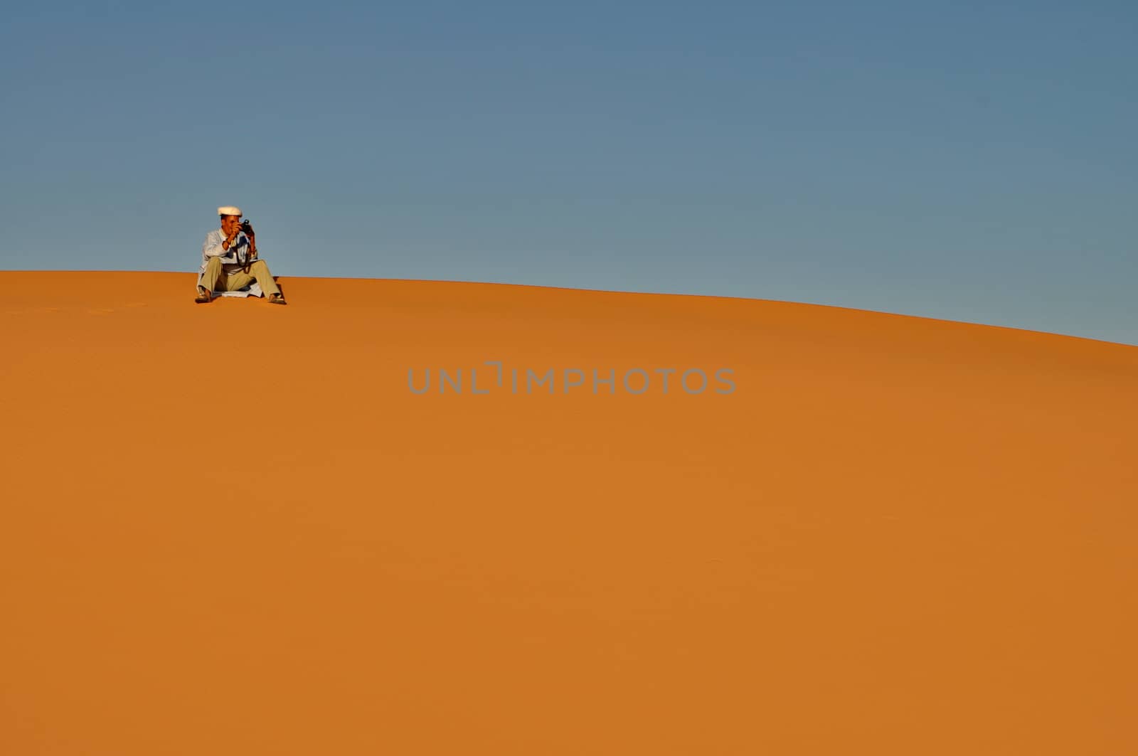 MERZOUGA DESERT - OCTOBER 01: Man in traditional Berber wear taking photograph in Merzouga Desert, Morocco on October 01, 2013.