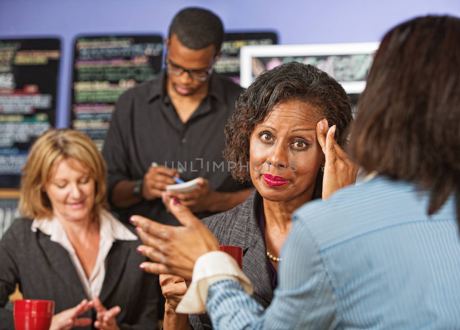 Overwhelmed female business person with headache listening to friend