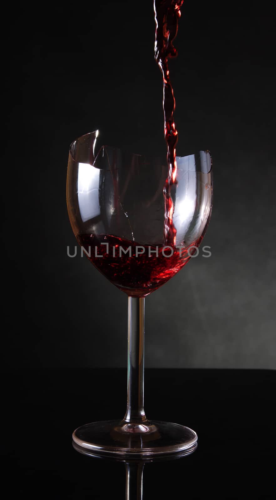 Pouring red vine into a broken glass by anderm