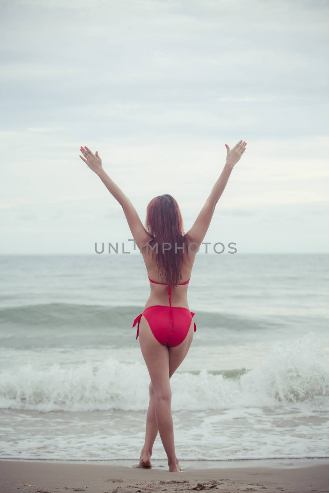 Sexy back of a beautiful asian woman in red bikini on sea background