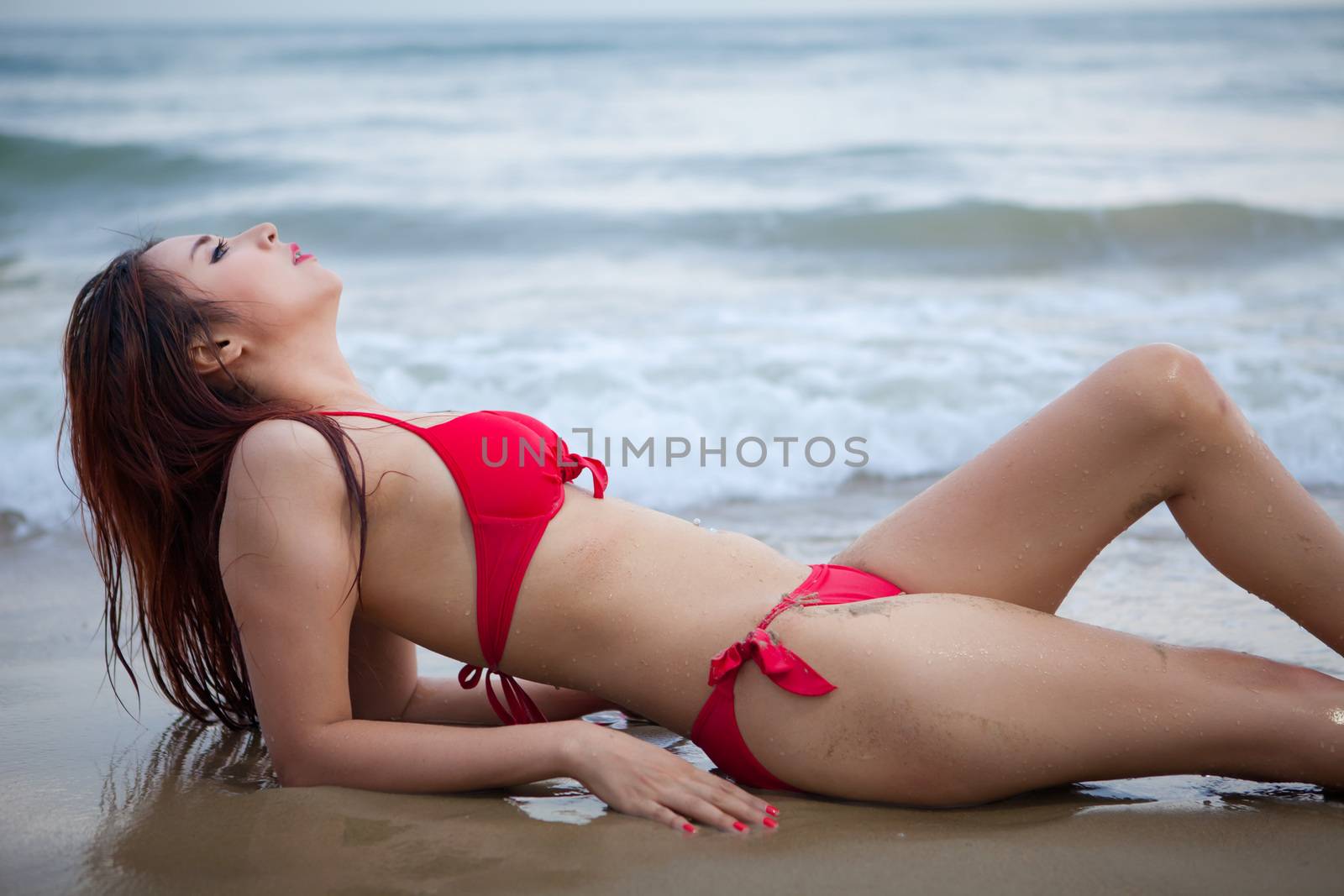 Beautiful sexy asian woman in red bikini posing at beach and sea