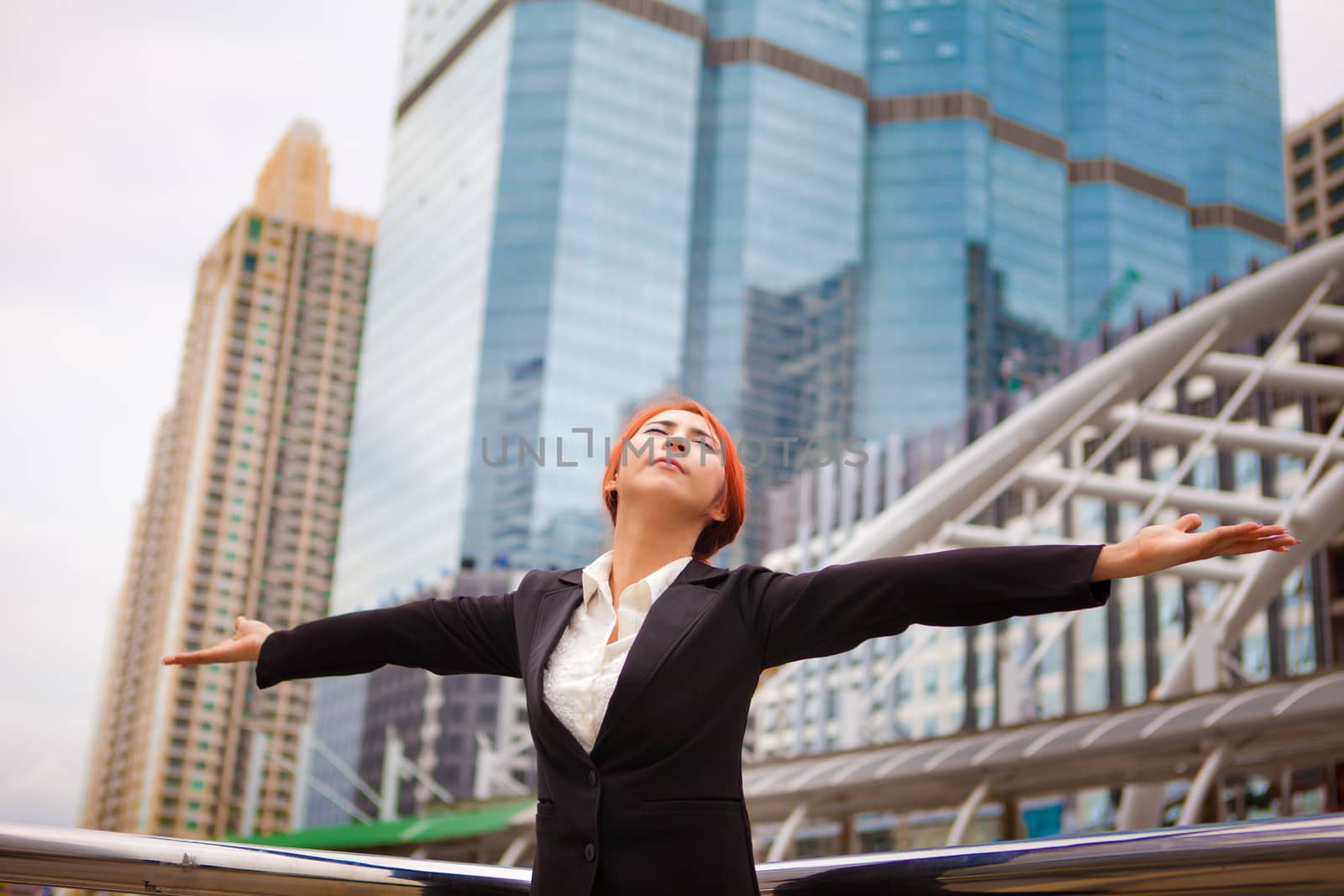 Young business asian woman outdoor with hands spread in modern city