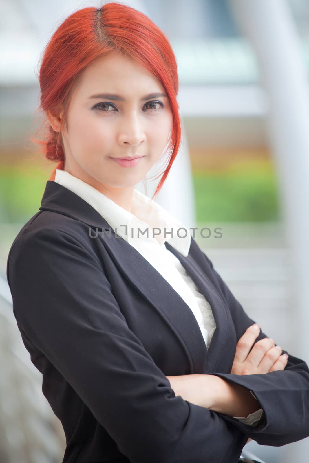 Portrait of young business asian woman standing and smiling arms crossed in modern city