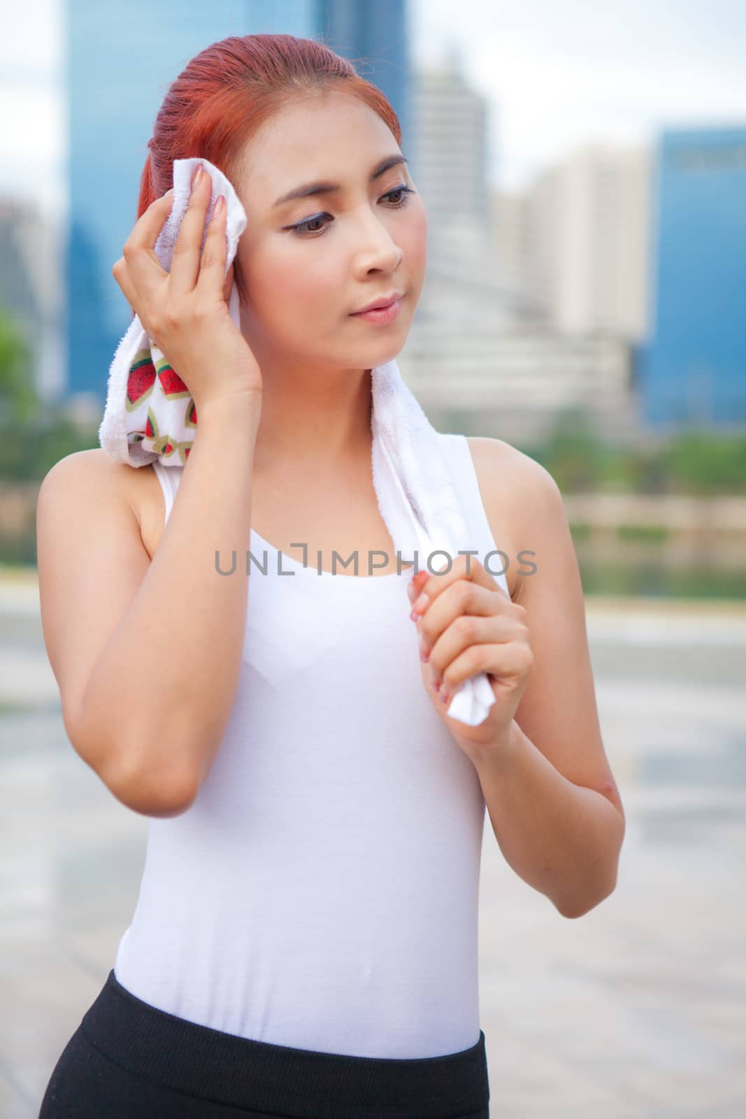 Young asian woman athlete wiping her towel in park city