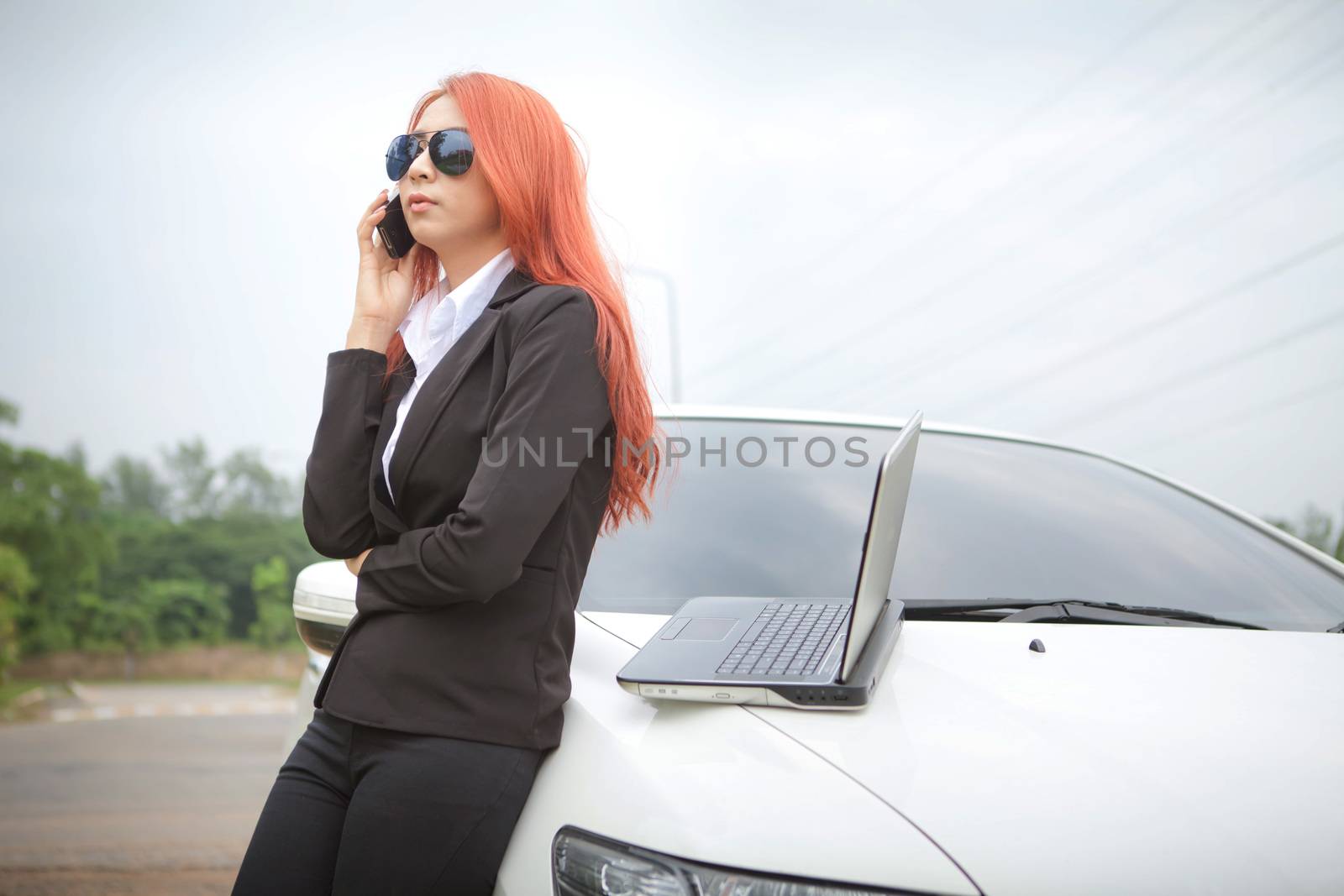 Beautiful young business asian woman using laptop and mobile phone and car