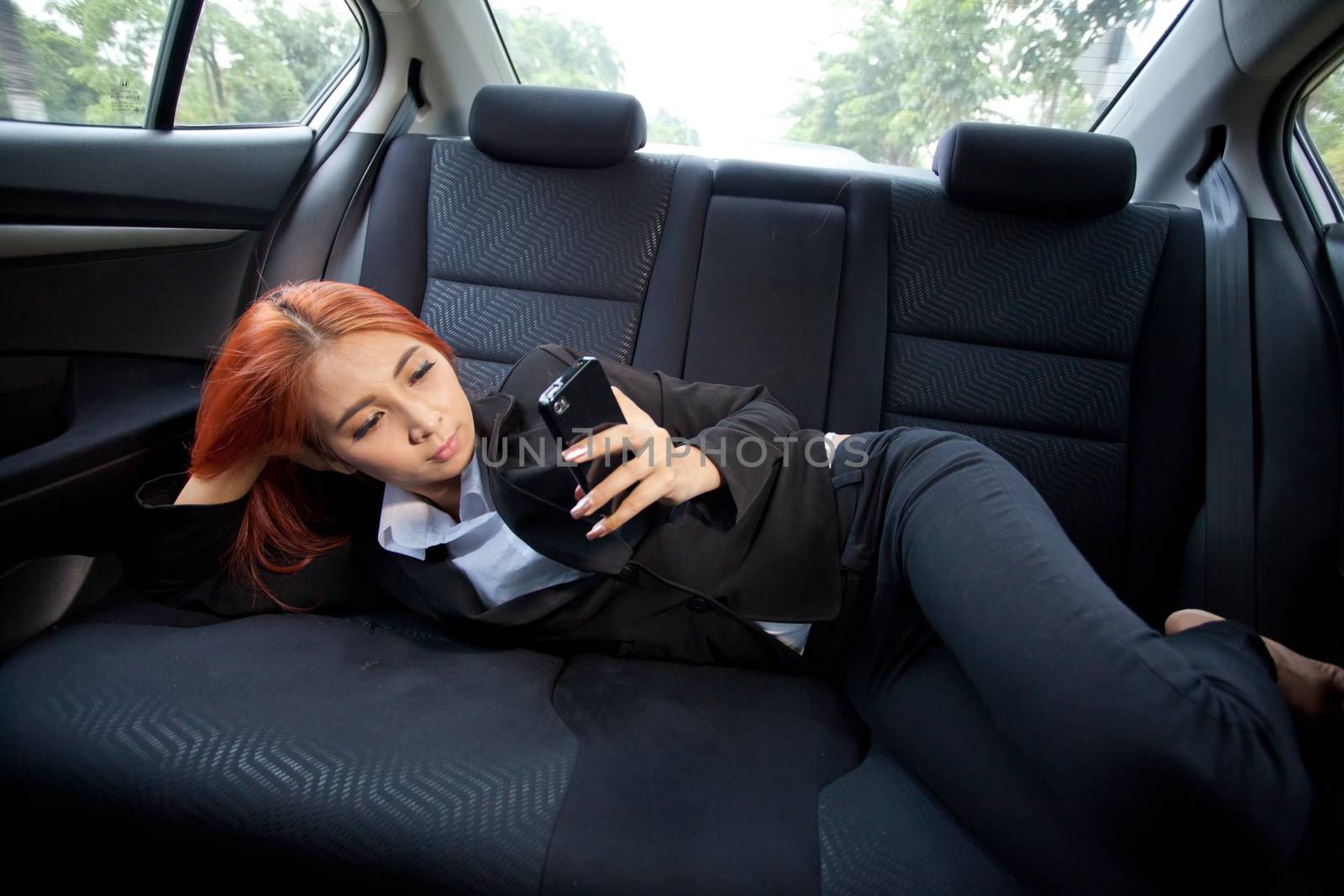 Beautiful young business asian woman using a smart phone in a car