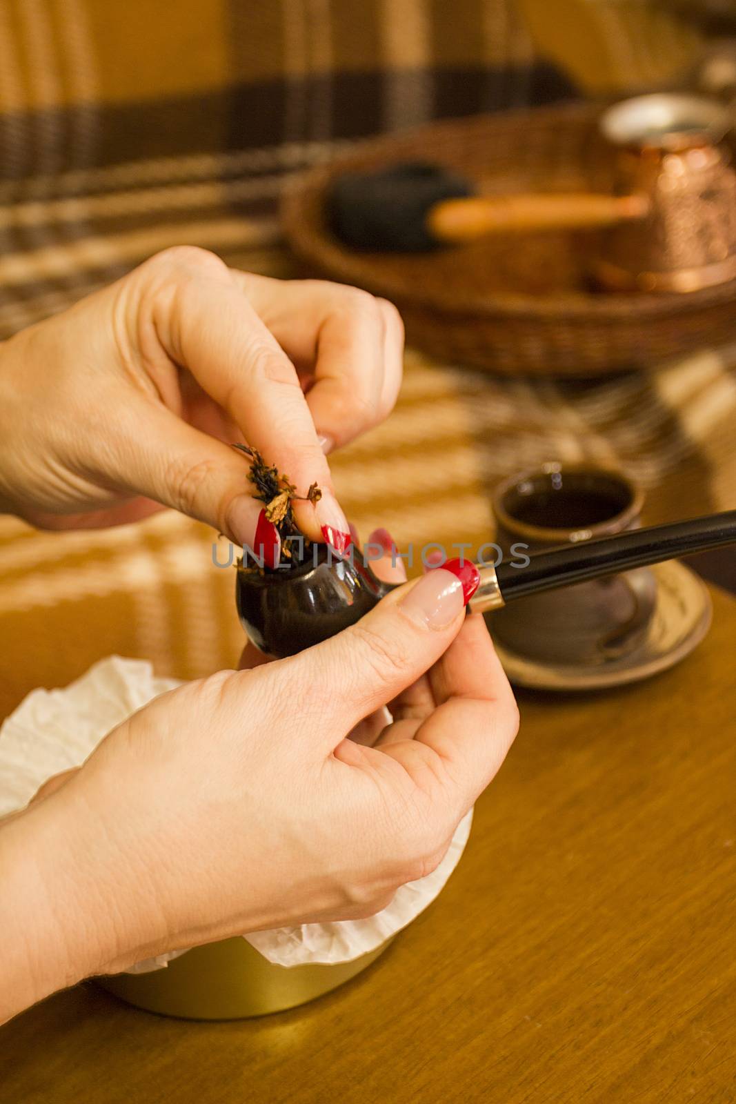 Female hands laying tobacco smoking pipe.