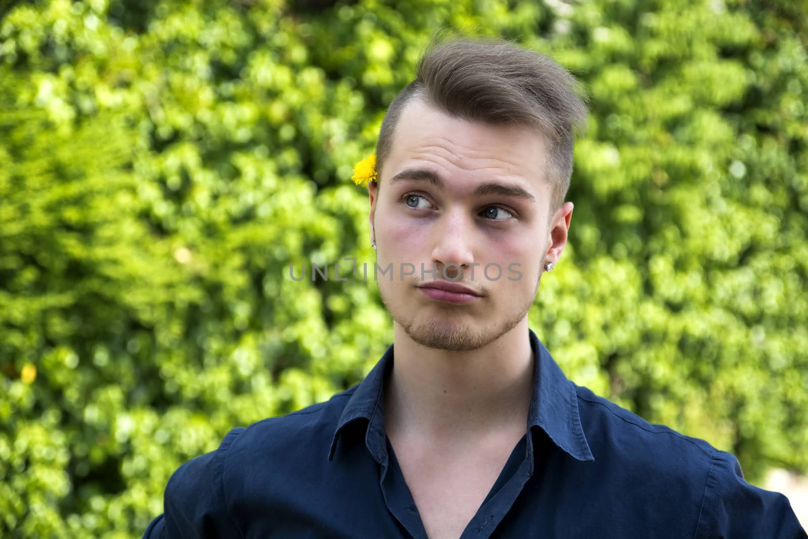Attractive young man with unsure expression, thinking. Outdoors shot