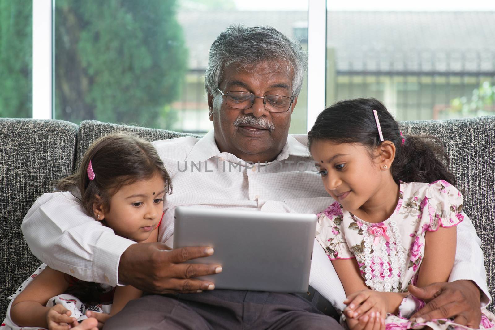 Portrait Indian family at home. Grandparent and grandchildren using digital tablet computer. Asian people living lifestyle.